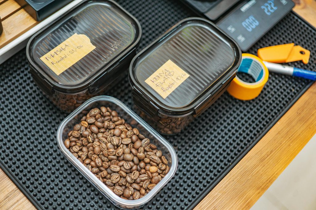 Roasted coffee beans in labeled containers on a table, ready for sampling or storage.